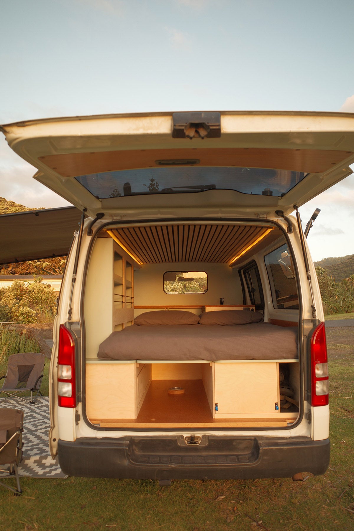 Campervan interior with bed setup in a natural outdoor setting