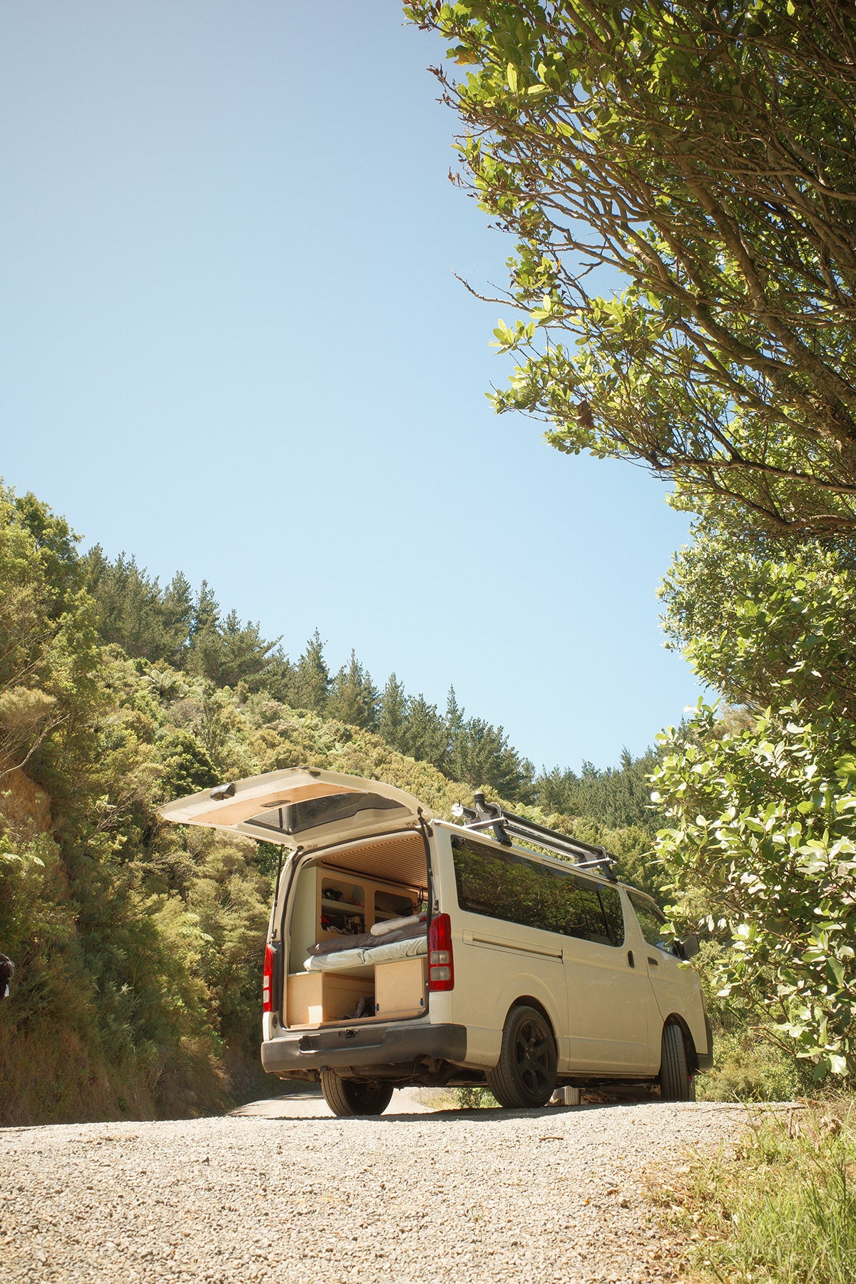Van with an open roof rack and storage compartments on a forest road